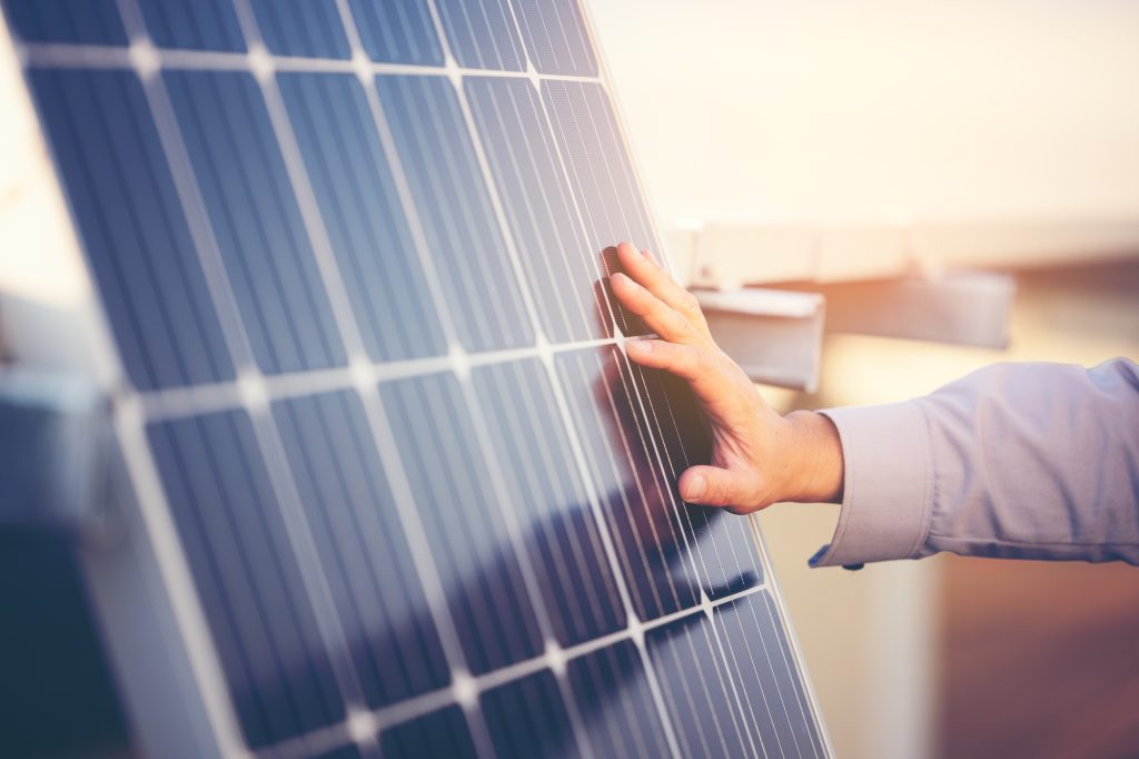 Close up of engineer hand is checking an operation of sun and cleanliness of photovoltaic solar pane